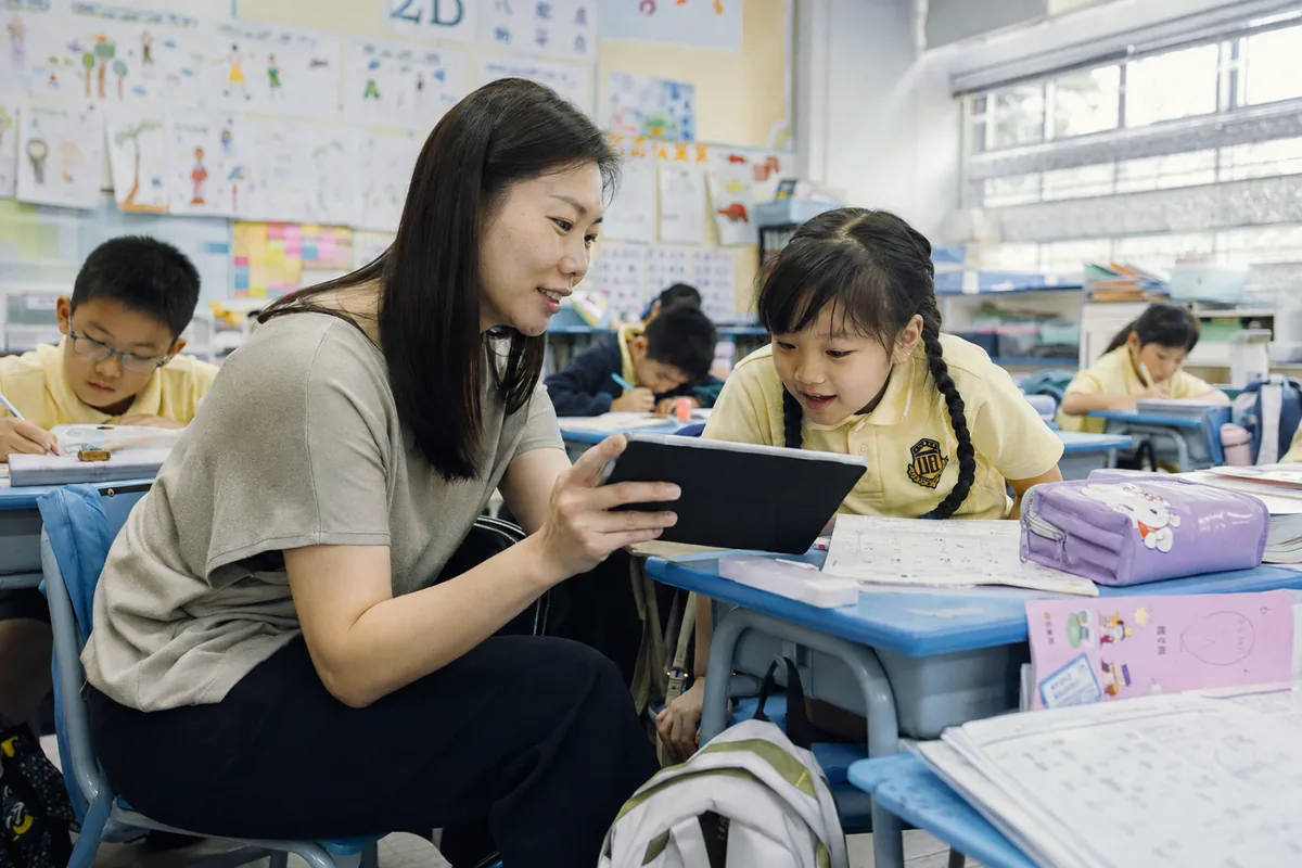 A teacher reviewing a lesson plan with a student in the classroom